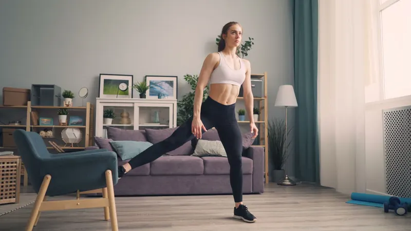 A woman in sportswear stretches in a stylish living room, engaging in home exercise